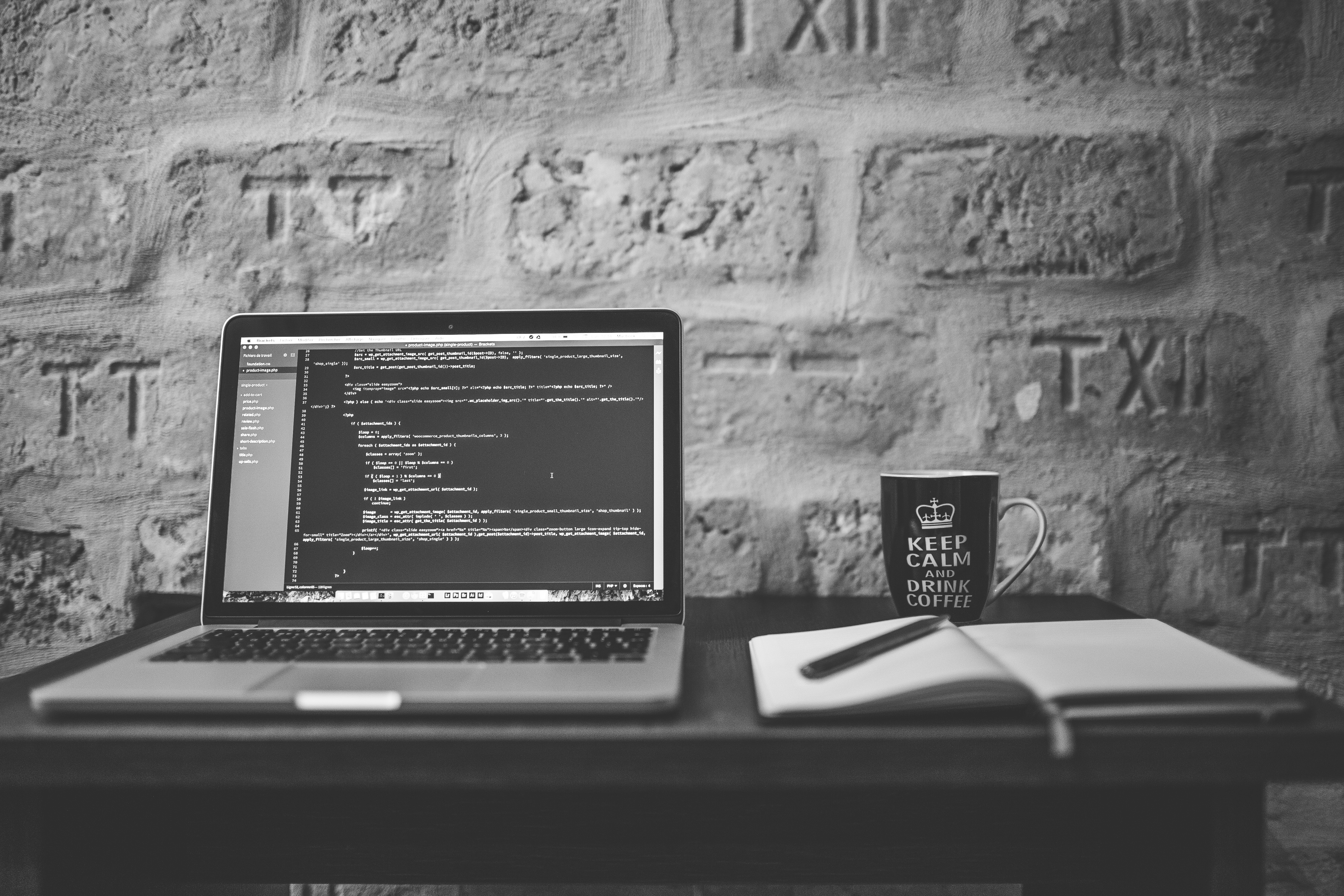 negative space grayscale photo of computer laptop near white notebook and ceramic mug on table