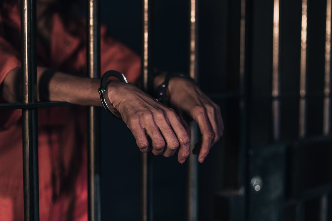 Handcuffed Prison Bars